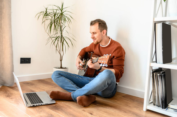 A guy watches video tutorial on guitar playing - Фото, зображення