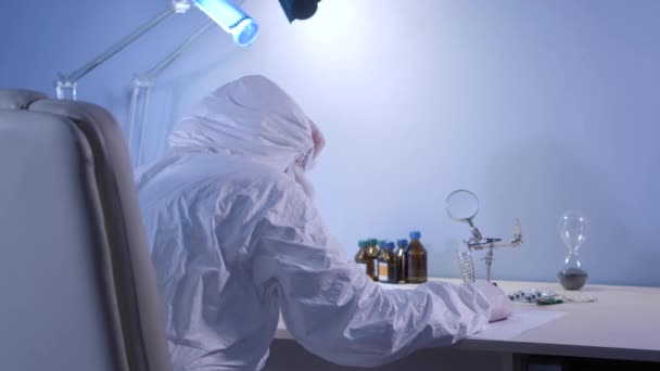 Back view of health care worker in protective suit lying on table. Tired doctor having break during Covid-19 pandemic. Coronavirus, virus, infection, health care, lifestyle. - Imágenes, Vídeo