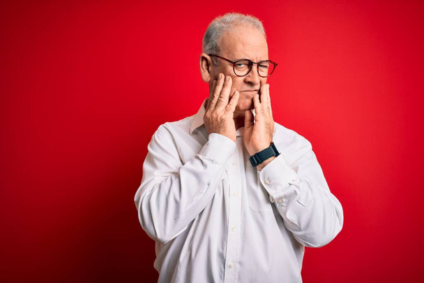 Middle age handsome hoary man wearing casual shirt and glasses over red background Tired hands covering face, depression and sadness, upset and irritated for problem - Фото, зображення