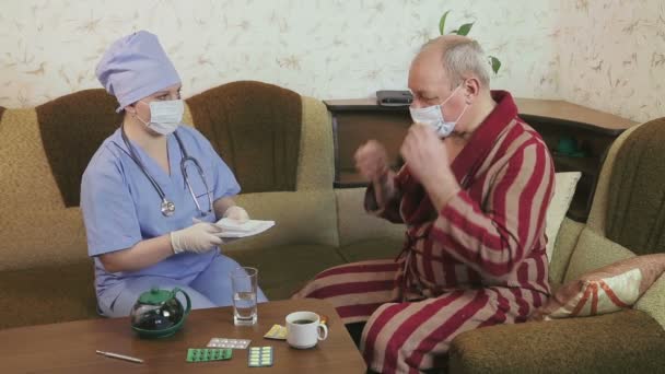 A female doctor instructs a hospital patient at home to take medicine. A man drinks pills. - Filmati, video