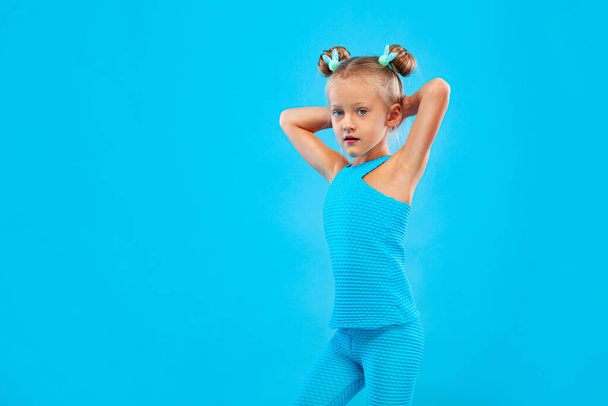 Kid girl doing fitness exercises on pink and pink background in sportswear. Sports concept. - Foto, imagen