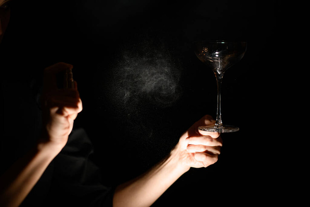 close-up bartenders mão mantém vazio vidro transparente e spray para ele
 - Foto, Imagem