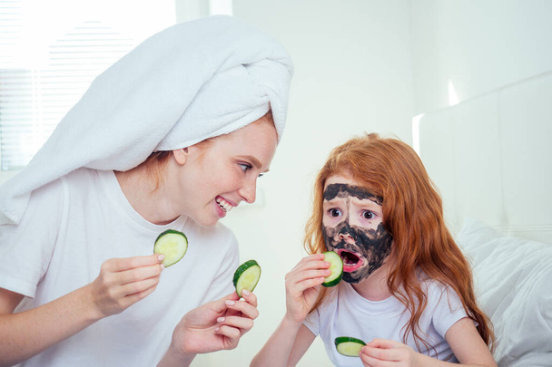 cute foxy hair little girl and redhaired ginger mother applying clay mask at bedroom beautican girlish spa day - Fotografie, Obrázek