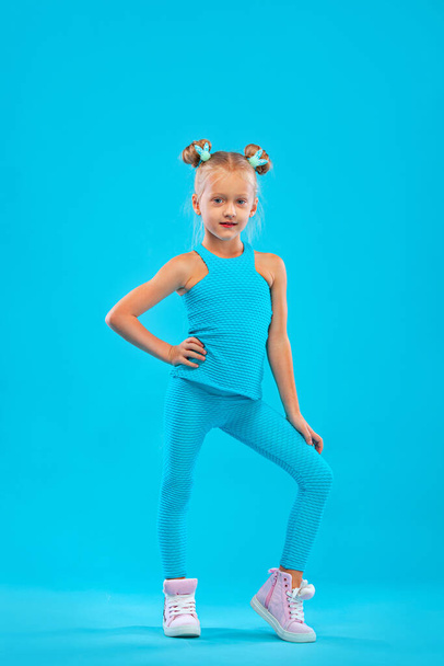 Kid girl doing fitness exercises on pink and pink background in sportswear. Sports concept. - Valokuva, kuva