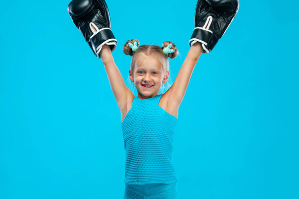 Boxing and fitness concept. Sportsman, girl kid boxer fighting in gloves on blue background. - Fotografie, Obrázek