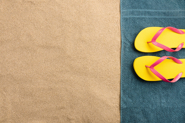 Top view flip flops on towel with copy space. Traveler accessories on sand. Travel vacation concept. Summer background - Фото, изображение