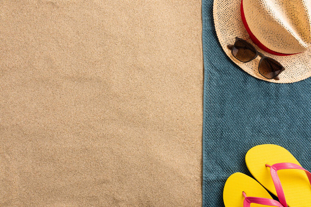 Top view of sandy beach with towel frame and summer accessories. Background with copy space and visible sand texture. Border composition made of towel - Фото, изображение
