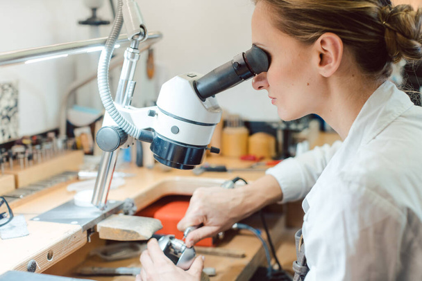 Joyero diligente trabajando en microscopio en su banco de trabajo - Foto, imagen