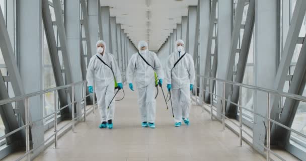 Grupo de desinfectantes en materiales peligrosos que caminan en el edificio público
 - Imágenes, Vídeo