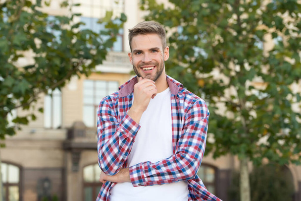 Cool about being scruffy. Unshaven guy smile urban outdoor. Happy man with unshaven face. Bachelor in plaid shirt. Unshaven look. Barbershop. Hair salon. Mens grooming habit. Young and unshaven - Fotoğraf, Görsel