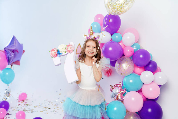 Unicorn Girl holding gold confetti air baloon and letter 7. Idea for decorating unicorn style birthday party. Unicorn decoration for festival party girl - Photo, image