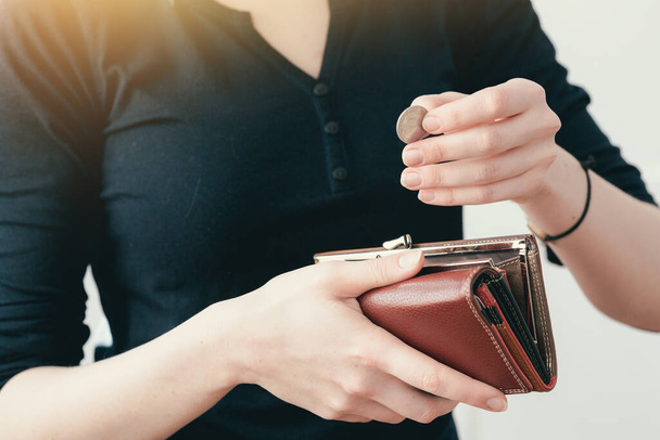 Woman in a black jacket pulls out coins from a leather purse. Cash to make purchases. - Foto, Imagem