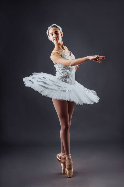 Граціозний танцівник балету або класична балерина, що танцює ізольовано на сірому фоні студії. Танець, грація, митець, сучасник, рух, дія і кіноконцепція. Лебединий костюм озера - Фото, зображення