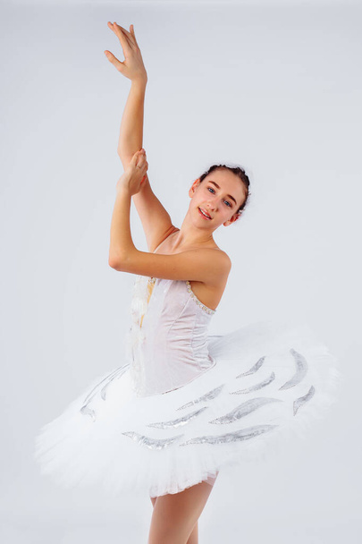 Atractiva bailarina joven con un hermoso cuerpo en maillot bailando puntillas en fotoestudio aislado sobre fondo blanco. Mostrando la belleza del arte clásico como el ballet
. - Foto, Imagen