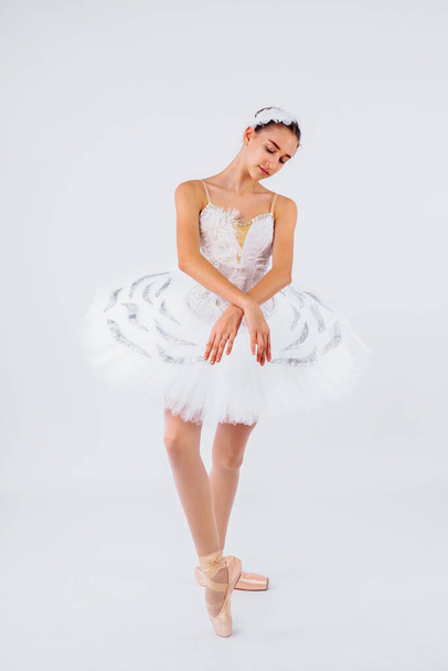 Dicsőség, álom, koreográfia. Karcsú nő balett táncos a stúdióban fények visel gyönyörű tutu hattyú tó balett előadás. Megfordulni, mint szobor a zenedobozban. - Fotó, kép