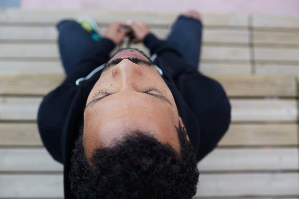 Pohled shora portrét Afroameričana sedícího na lavičce v parku v neformálním oblečení. Vodorovně. - Fotografie, Obrázek