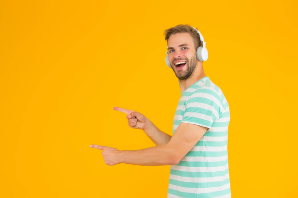 Listening heroic music feeling more positive motivated active and inspired. Man pointing copy space. Perfect sound concept. Happy Man listen music headphones. Wireless headphones. Instrumental music - Foto, afbeelding
