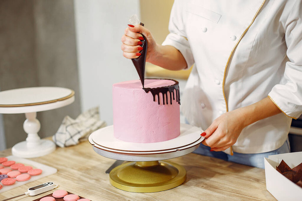 Confectioner in a uniform decorates the cake - Фото, изображение
