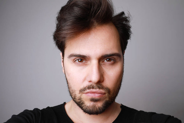 Headshot de hombre con estilo serio se ve recto con expresión de confianza, posando sobre fondo gris
. - Foto, Imagen