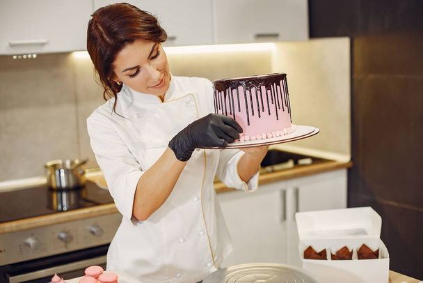 Confectioner in a uniform decorates the cake - Foto, Bild