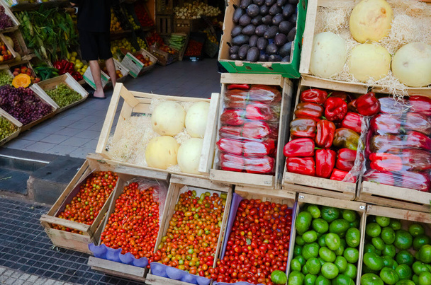 Marketten alışveriş yapan bir sokak satıcısı. Sebzeler ve meyveler marketin yakınındaki caddenin dışındaki tahta kutularda. Kırmızı biber, kiraz domatesleri, kavun ve küçük yeşil balkabakları. Buenos Aires, Arjantin. - Fotoğraf, Görsel