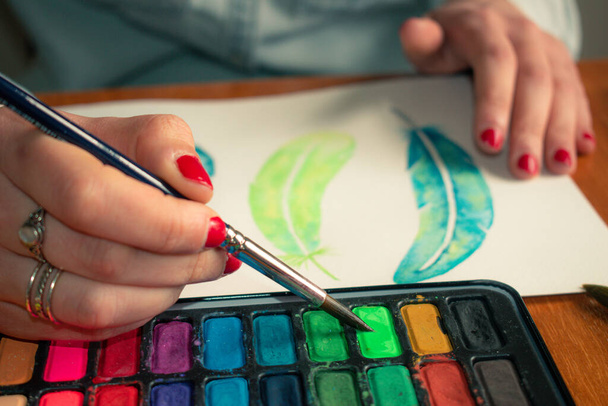 Mão close-up da senhora com unhas vermelhas preparando cores para a pintura de penas de aquarela
 - Foto, Imagem
