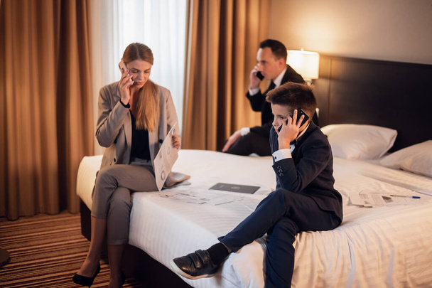 Eine dreiköpfige Familie telefoniert in einem Hotelzimmer - Foto, Bild