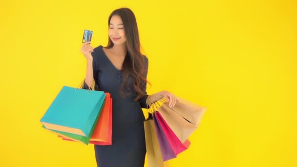 felvétel gyönyörű ázsiai nő színes bevásárló táskák elszigetelt sárga - Felvétel, videó