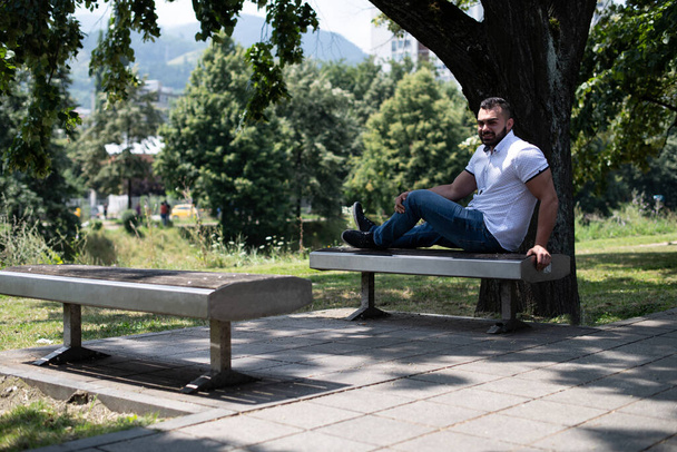 Portrait of a Confident and Successful Young Man With White Shirt Outside in Park Sitting on Bench - Fotografie, Obrázek