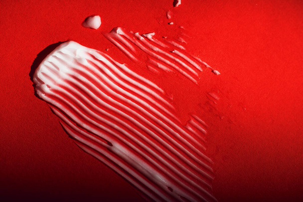 smear of natural cream. red background. - Фото, изображение