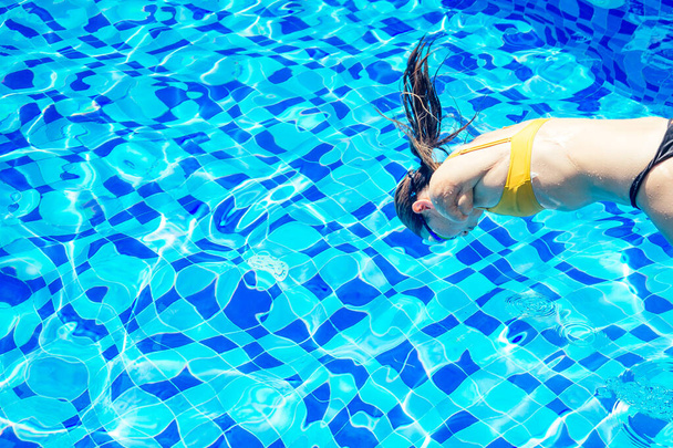 beautiful young armless woman training to swim in pool at tropical resort - Zdjęcie, obraz