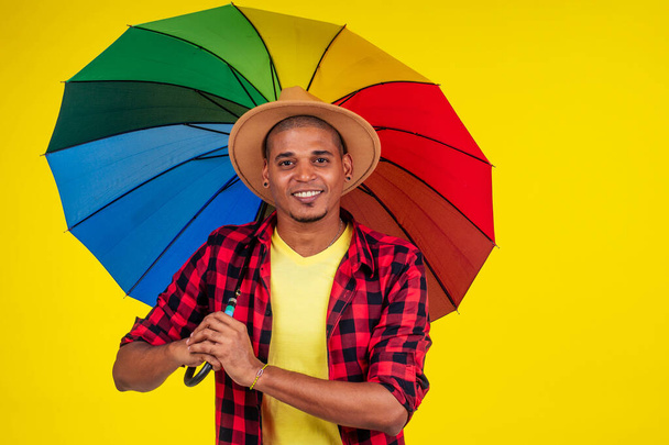 latino brasiliano uomo con ombrello arcobaleno vicino al colore giallo parete
 - Foto, immagini
