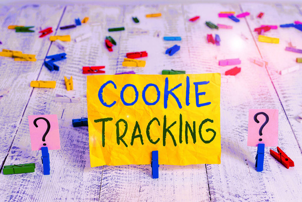 Cookie Tracking 'i gösteren kavramsal el yazısı. Kullanıcı bilgisayarında saklanan iş fotoğrafı metni verileri, web sitesi tarafından ziyaret edilip tahta masaya ataçlarla parçalanır.. - Fotoğraf, Görsel