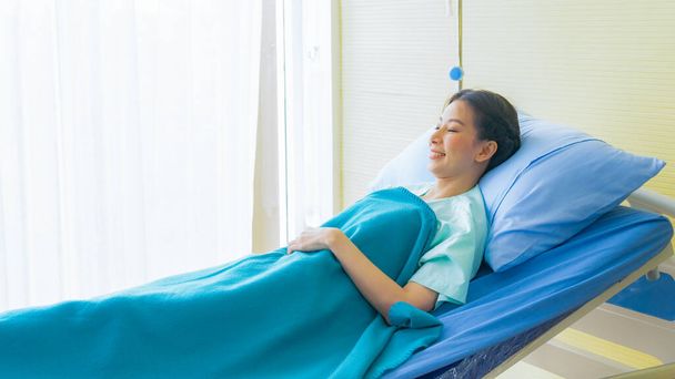 Aasialainen tyttö potilas sängyssä sairaalassa tausta valkoinen verho. - Valokuva, kuva