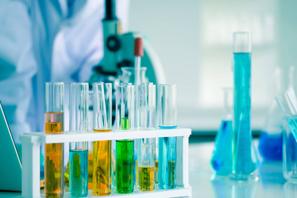Close-up shot of science laboratory test tubes. Liquid many colors in equipment glassware for chemistry biology samples. Blur background is scientist experimenting with tube and microscope. - Foto, Imagen