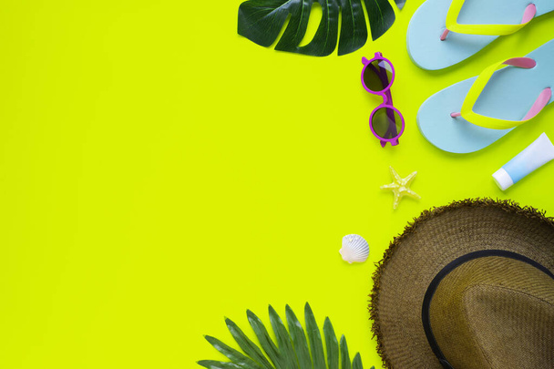 Summer holiday of traveler men or women. Top view from above of beach accessories and hat with sunglasses and sandals on yellow background. Flat lay with copy space. Tropical fashion vacation concept. - Foto, afbeelding