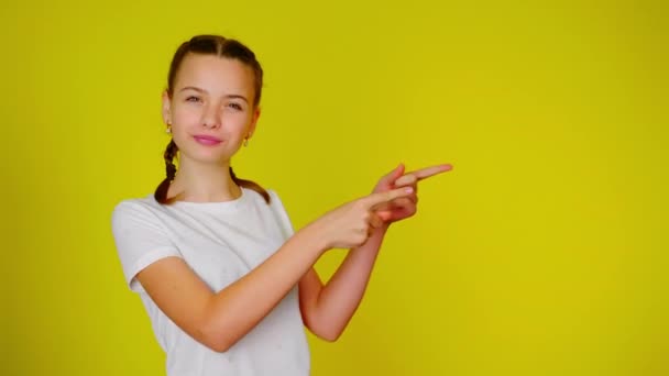 Ένα έφηβο κορίτσι με λευκό μπλουζάκι δείχνει ένα μέρος για κείμενο. - Πλάνα, βίντεο
