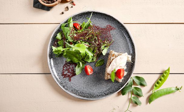 Jerked duck, smoked cream cheese and garlic ciabatta salad in gray plate top view. Fresh food, healthy eating close up. Greenery and tomato decorations. Restaurant menu meal, served gourmet appetizer - 写真・画像