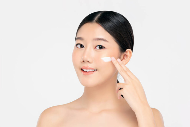 jong mooi aziatisch vrouw met fris schoon uiterlijk toepassing crème naar gezicht geïsoleerd op witte achtergrond voor schoonheid en huidverzorging concepten - Foto, afbeelding