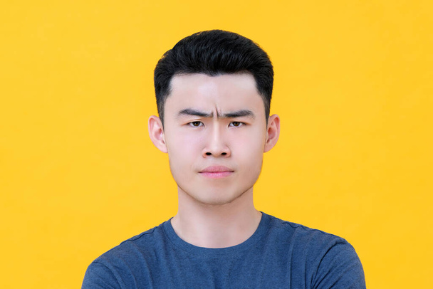 close-up portret van ongelukkige boos jong aziatische man gezicht geïsoleerd op gele achtergrond - Foto, afbeelding