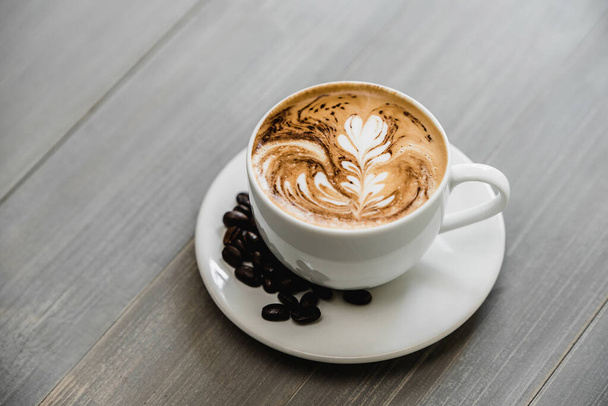 Fresh brewed coffee with fern pattern latte art in white cup on wood tabble - Foto, Imagen