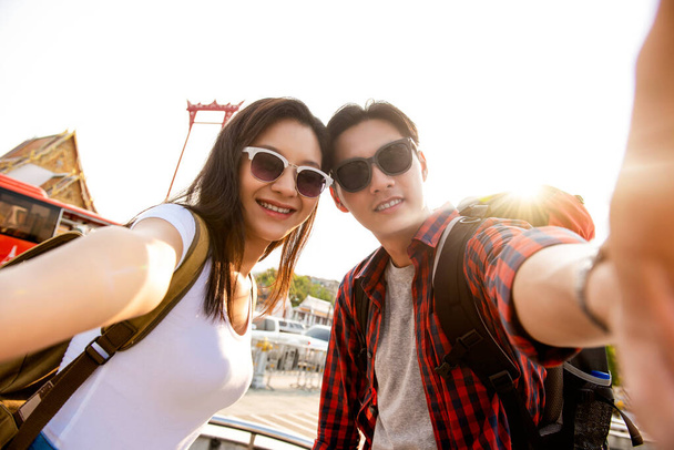 Asian couple tourists taking selfie while traveling on summer vacations in Bangkok Thailand - Photo, Image