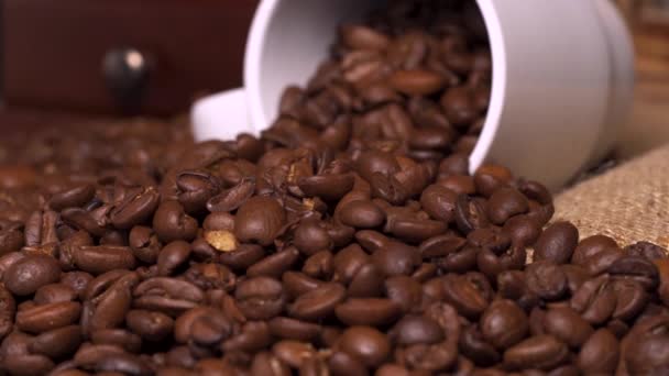 Biały kubek kawy i ziarna kawy w zwolnionym tempie - Materiał filmowy, wideo
