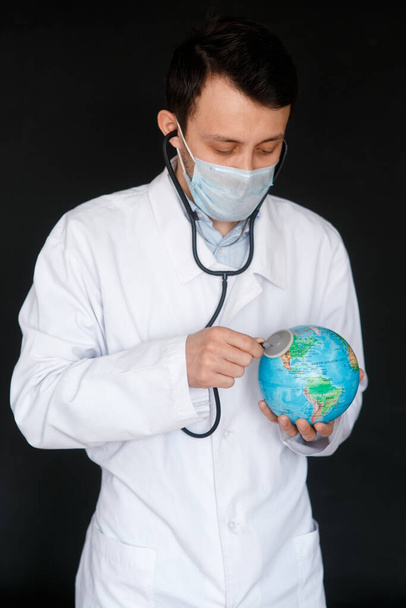 A doctor with a stethoscope auscultates the respiration of the lungs of the planet Earth - pneumonia and coronavirus in the USA - medical diagnostic - Φωτογραφία, εικόνα