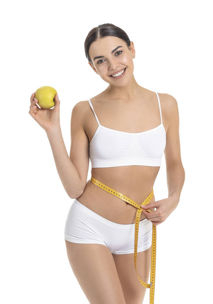 Mladá žena s jablkem a měřicí páskou na bílém pozadí. Koncept hubnutí - Fotografie, Obrázek