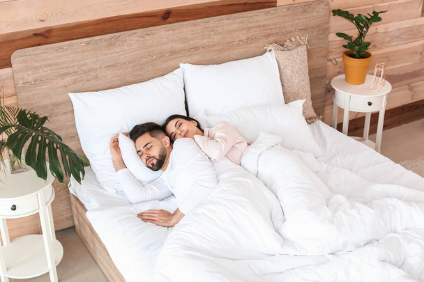 νεαρό ζευγάρι κοιμάται στο κρεβάτι στο σπίτι - Φωτογραφία, εικόνα