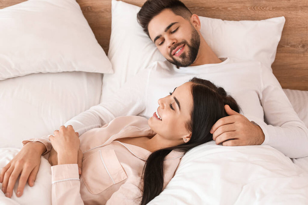 Happy young couple lying in bed at home - Foto, Bild