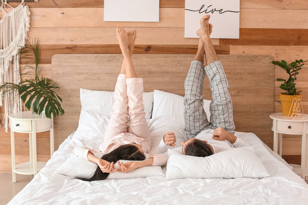 Счастливая молодая пара лежит в постели дома - Фото, изображение