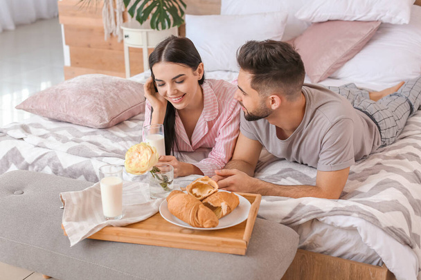 Jeune couple prenant le petit déjeuner au lit à la maison
 - Photo, image