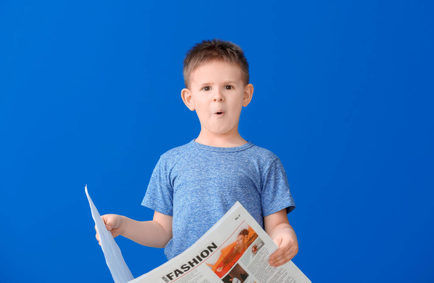 Shocked little boy reading newspaper on color background - Foto, Imagem